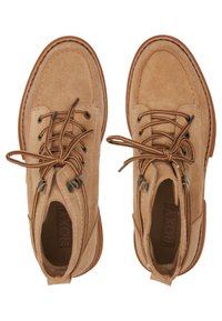 Bottines en suède tan avec un bout arrondi, un laçage à l'avant, des œillets en métal et un accès par une fermeture éclair sur le côté. Surface texturée avec des détails cousus.