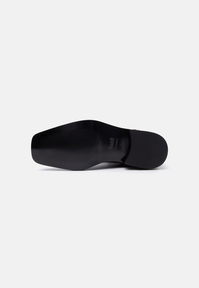Sole of a black formal shoe with textured grip and slight heel, displayed against a plain light background.