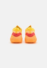 Baskets jaunes avec un design dégradé, dotées d'une semelle orange texturée et d'accents rouges. Onglets à l'arrière pour un enfilage facile.