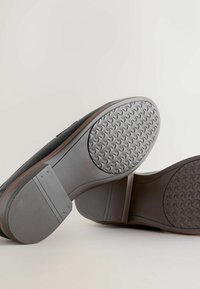 Mustad mustad mustadega kummitaldadega mustad kingad, mis esitlevad sileda viimistlusega ja pruuni aktsendiga servas. Omavad üksikasjalikku tallamustrit.