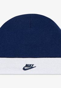 Ναυτικό μπλε πλεκτό σκουφάκι με λευκό ρέλι, με κεντημένο λογότυπο Nike σε ναυτικό χρώμα. Μαλακή υφή, στρογγυλή κορυφή.