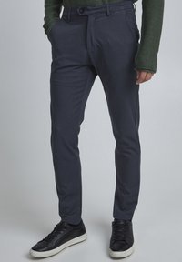 Grå skräddarsydda byxor i strukturerat tyg, med flat front, sidfickor och slim fit, kombinerat med svarta sneakers.