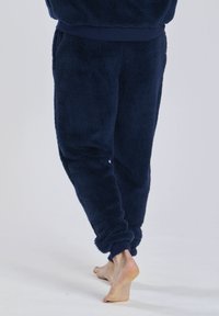 Marineblaue Fleece-Jogginghosen mit elastischen Bündchen; weiche Textur; enger Sitz an den Knöcheln; keine sichtbaren Taschen oder Metallteile.