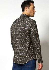 Langärmliges Hemd in Dunkelgrün mit Blumenmuster. Aus strukturiertem Stoff mit einem Button-Down-Kragen und abgerundetem Saum.