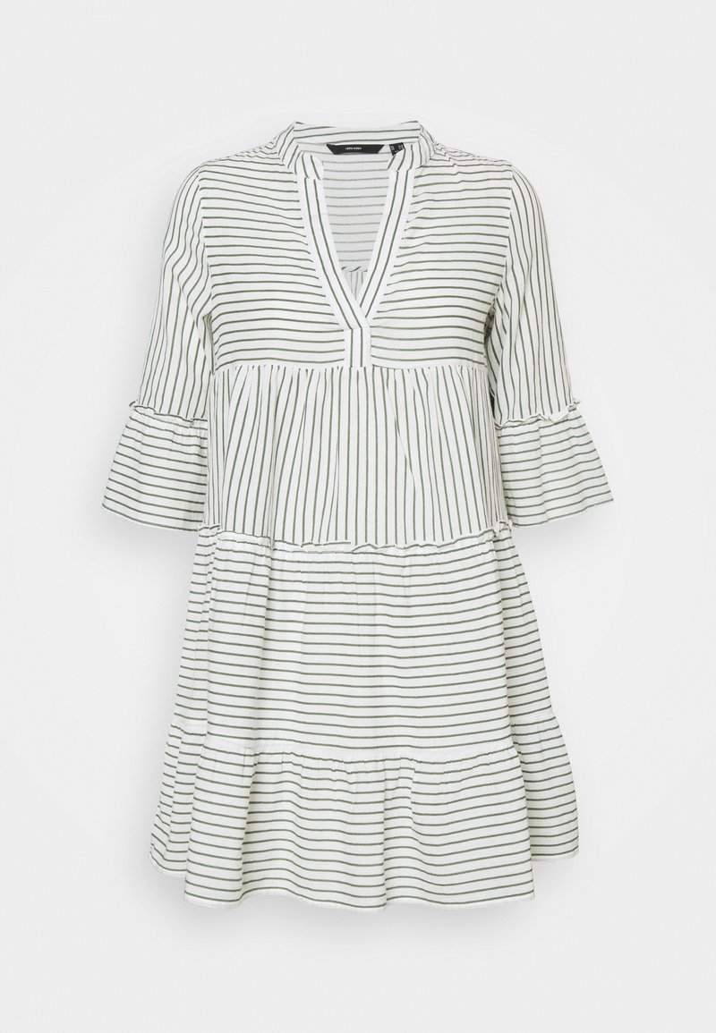 Valkoinen mekko, jossa on viistot vihreät raidat, V-pääntie ja kolmanneksen pituiset kellohihat. Mekossa on kerroksellinen muotoilu ja röyhelöhelma.