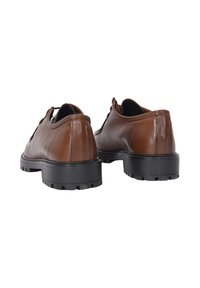 Scarpe in pelle marrone con una texture liscia, forma arrotondata e suola in gomma nera con battistrada per la trazione. Visibili lacci e dettagli di cucitura.