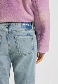 Denimjeans i ljusblått med en lätt blekning, med en blå HUGO-logotyp på midjebandet och en subtil design på bakfickan.