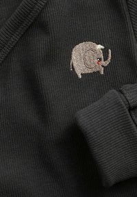 Sort strikket stof præsenterer et lille, broderet elefantdesign i lys grå med lyserøde accenter, placeret på venstre side tæt på kraven.