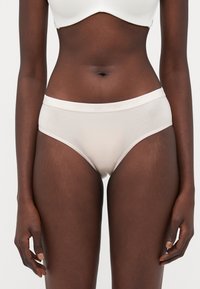 Light beige cotton hipster underwear with a soft elastic waistband. The fabric is smooth and slightly sheer, featuring minimalistic design.