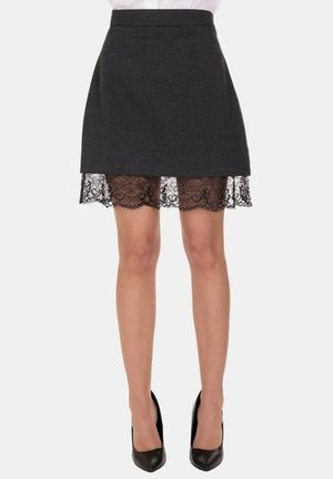 Gonna nera al ginocchio con uno strato superiore di tessuto testurizzato e orlo in pizzo, caratterizzata da una silhouette dritta e una vita sottile.