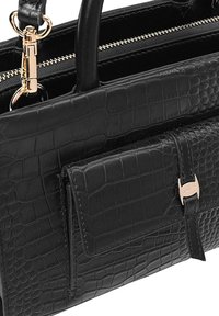 Zwarte krokodillen-embossed leren tas met twee handvaten, gouden hardware en een voorvak. Voorzien van een ritssluiting en een gestructureerde oppervlakte.