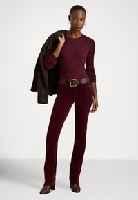 Bordó testhez simuló felső hosszú ujjakkal, hozzá illő bordó kordbársony bőszárú nadrággal párosítva. Sötétbarna öv fém csattal és kockás dzseki.