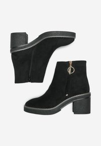 Black suede ankle boots with a chunky heel, featuring a side zipper and circular hardware accent. Smooth texture with contrasting sole trim.