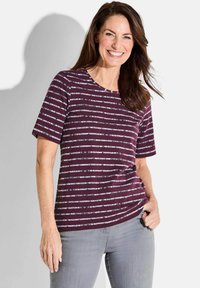 Kurzärmliges burgunderfarbenes T-Shirt mit weißen horizontalen Streifen, Rundhalsausschnitt, aus weichem Stoff, kombiniert mit hellgrauen Jeans.