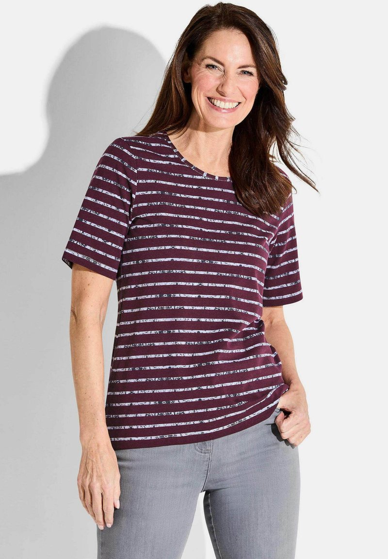 Kurzärmliges burgunderfarbenes T-Shirt mit weißen horizontalen Streifen, Rundhalsausschnitt, aus weichem Stoff, kombiniert mit hellgrauen Jeans.