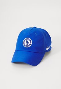 Blå baseballcaps i bomull med en rund skärm. Framsidan har en cirkulär Chelsea Football Club-logga; sidan har en vit Nike swoosh.