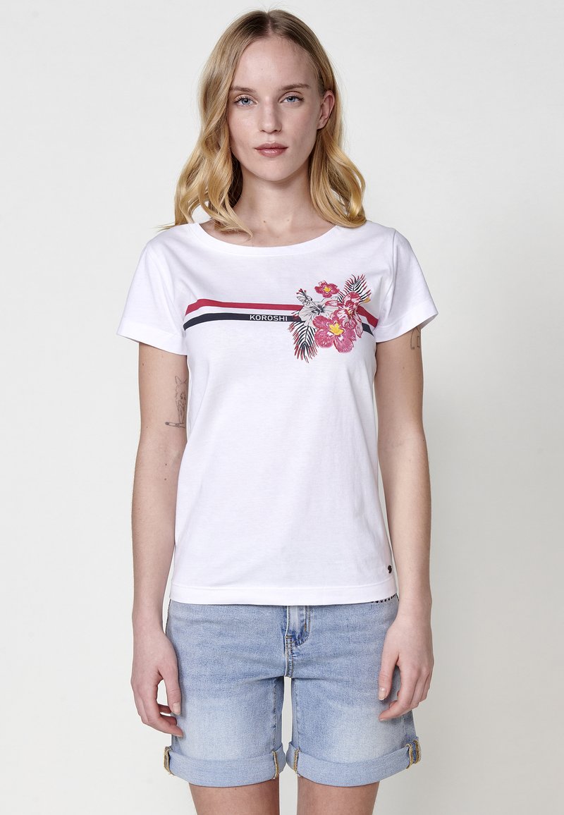 Camiseta blanca de manga corta con estampado floral en rosa y verde, acompañada de rayas rojas y navy cerca del escote. Tejido de algodón suave.