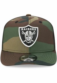 Tarnmütze mit strukturiertem Kopfteil, verstellbarem Riemen und einem auffälligen schwarzen und weißen Raiders-Logo auf der Vorderseite.