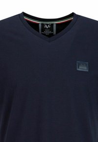 Navyblauwe V-hals T-shirt van zachte stof met een klein reliëflogo op de linkerkant van de borst en een contrasterende gestreepte halslijn.