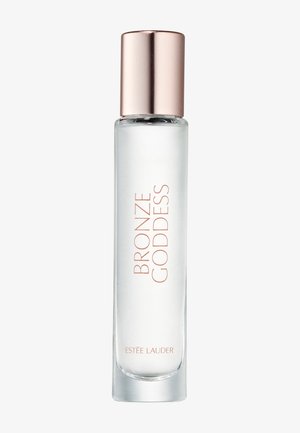 Flacon en verre transparent avec bouchon en or rose étiqueté « Bronze Goddess » et produit parfumé ou cosmétique « Estée Lauder ».