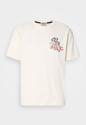 Cremfarbener T-Shirt aus Baumwolle. Mit einem bunten gestickten Design auf der Brust, das Text und ein Gebäudemotiv zeigt. Kurze Ärmel.