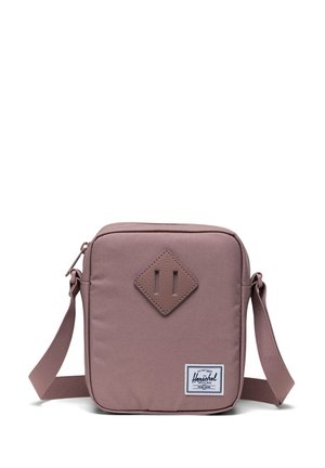 Firkantet, mauve crossover taske med tekstureret stof, diamantaccent foran, justerbar rem og et logo-label nederst til højre.