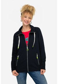 Chaqueta de nylon azul marino con cierre, cuello alto, detalles en verde contrastante en los cordones y dos bolsillos laterales. Textura de tela suave.