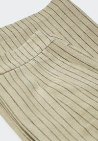 Beżowa tkanina w paski z pionowymi czarnymi liniami. Tekstura wydaje się gładka, z dopasowaną talią i plisowanym fasonem.