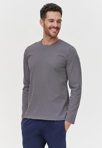 Koszula z długim rękawem w granatowym kolorze z białym wzorem w kratę. Posiada okrągły dekolt i luźny krój, wykonana z gładkiego materiału.