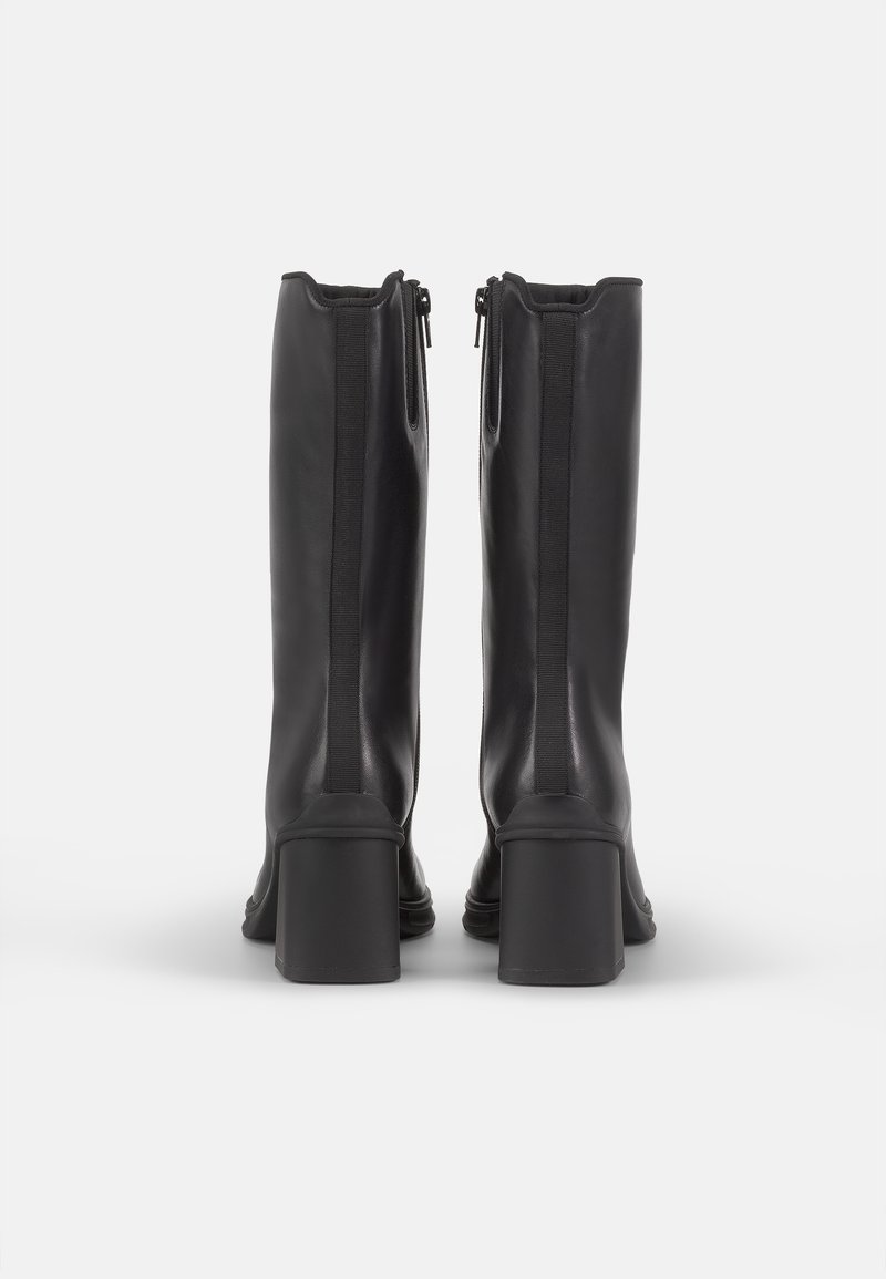 Botas negras de cuero hasta la rodilla con un tacón robusto, cremalleras laterales y acentos de elastano a lo largo de las costuras para ajustarse y facilitar su uso.