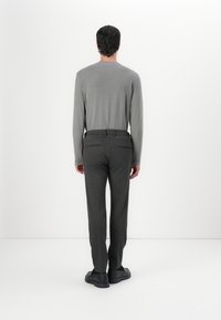 Grauer Langarmpullover kombiniert mit dunkelgrauen, flachen Hosen, die eine glatte Textur und ein minimalistisches Design aufweisen. Schwarze Schuhe vervollständigen den Look.