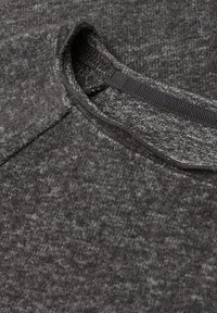 Sweatshirt grigio a maglia con collo rotondo e tessuto texturizzato caratterizzato da un sottile motivo a macchie. Bordo elasticizzato al collo.