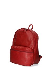 Sac à dos en cuir rouge avec une forme arrondie, deux compartiments zippés, une poignée supérieure et une texture lisse. Dispose d'une poche avant.