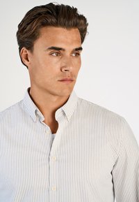 Πουκάμισο με κουμπιά σε ανοιχτό γκρι και λευκές ρίγες, με γιακά, στρογγυλεμένες άκρες και μικρά κουμπιά, κατασκευασμένο από λείο βαμβακερό ύφασμα.