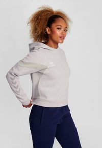 Felpa grigia chiaro con vestibilità comoda, caratterizzata da maniche texture, cappuccio e dettagli di logo sottili. Completata da pantaloni blu scuro.