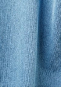 Tela de mezclilla azul claro que muestra una textura suave con un sutil tejido diagonal. El material es suave y ligeramente drapeado.