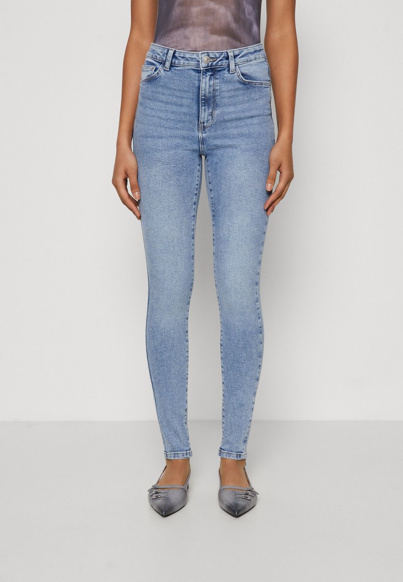 Lyseblå høytlivsskjorte jeans med en glatt denim tekstur, med knapp- og glidelås-lukking, samt frontlommer. Kombinert med grå leiligheter.