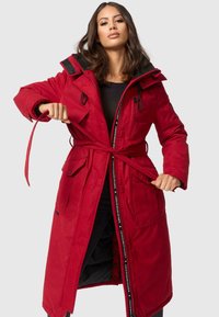 Manteau rembourré rouge avec fermeture éclair à l'avant et taille ceinturée. Il dispose d'une capuche, de deux poches latérales et de accents noirs le long de la fermeture éclair.