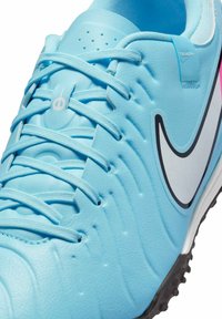 Light blue athletic shoe with a textured synthetic upper, white swoosh logo, and black rubber outsole. Laces and upper feature detailing.
