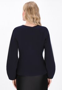 Marineblaues Langarmoberteil mit enganliegendem Design und V-förmigem Rückenausschnitt. Material wirkt glatt und hat keine sichtbaren Muster oder Beschläge.