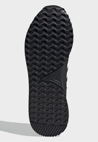 Svart sportsko sula med texturerat, vågigt mönster; har en central triangel-logotyp och vinklade spår för grepp.