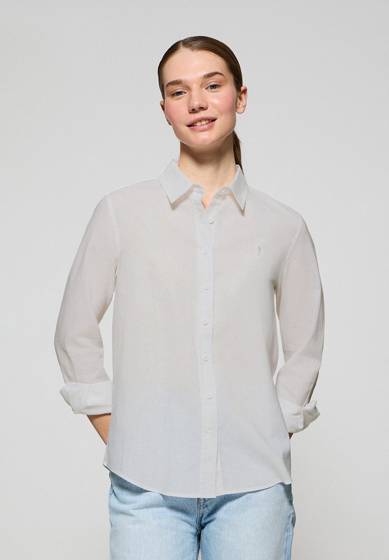 Biała koszula z długim rękawem, wykonana z lekkiego materiału, z kołnierzykiem i małym haftowanym logo na piersi.