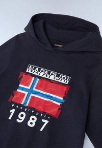 Sudadera azul marino con un gráfico frontal que presenta la bandera noruega en rojo, blanco y azul, incluyendo acentos de texto "NAPAPIJRI" y "1987".