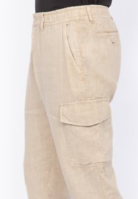 Beige cargobroek gemaakt van lichtgewicht stof, met meerdere zakken, een relaxte pasvorm en een elastische tailleband voor comfort.