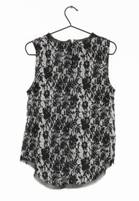 Top senza maniche in pizzo nero con motivi floreali, scollatura rotonda, leggero lucido e orlo leggermente curvato con etichetta appesa.