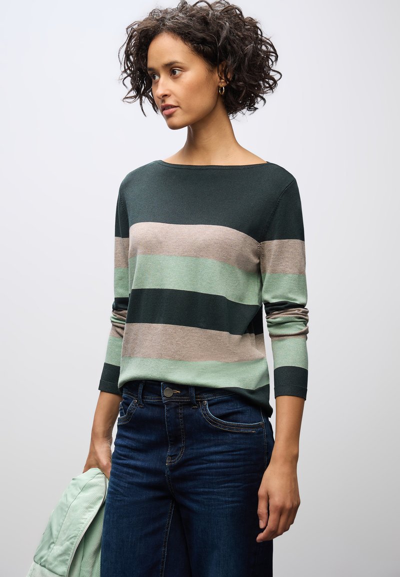 Gestreifter Pullover in dunkelgrün, weichem Mint und Beige. Mit Bootsausschnitt, langen Ärmeln und gerippten Bündchen. Kombiniert mit dunklen Jeans.