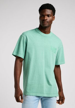 T-shirt vert menthe à manches courtes en tissu doux. Présente un col rond et un logo discret sur la poitrine. Coupe décontractée.