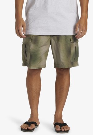 Kamouflaged cargo shorts i gröna nyanser, med två stora sidofickor, avslappnad passform och en slitstark tygtextur. Bärs med sandaler.