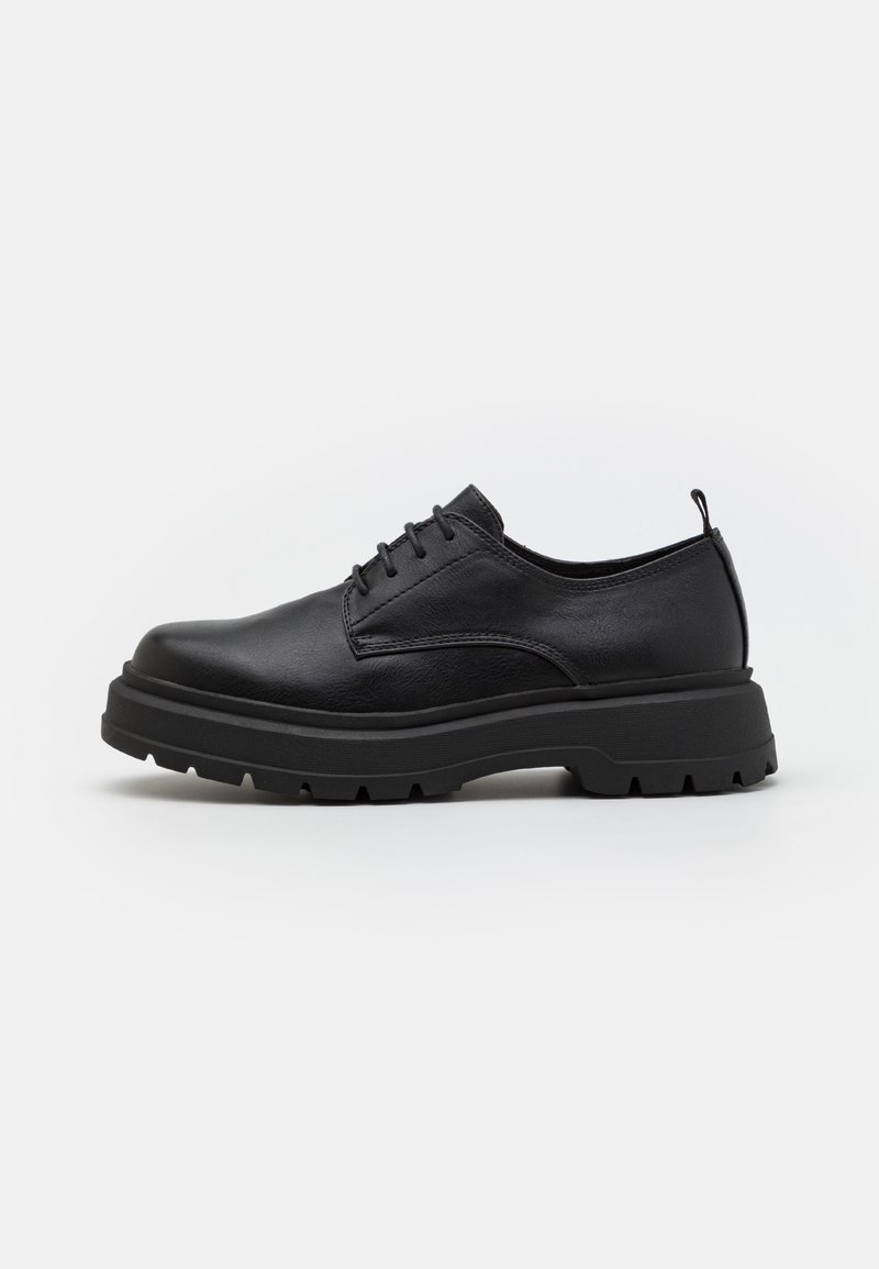 Scarpa in pelle nera con lacci, punta arrotondata, suola in gomma spessa e dettagli testurizzati. Presenta una linguetta sul tallone per facilitarne l'indossamento.