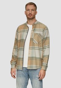 Geruite shirt in beige, groen en blauw met een knoopsluiting, lange mouwen, een borstzak en een off-white onderhemd. Spijkerbroek.